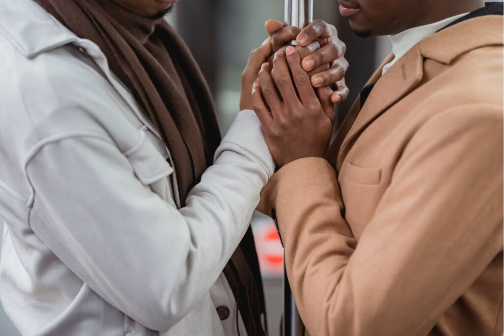 A Black couple, both partners male, hold each other's hands tenderly while facing each other, a hopeful outcome of trauma therapy for couples.